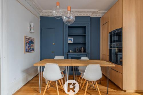 une salle à manger avec une table en bois et des chaises blanches dans l'établissement R'Apparts T3 Paris 9ème L'Incontournable, à Paris