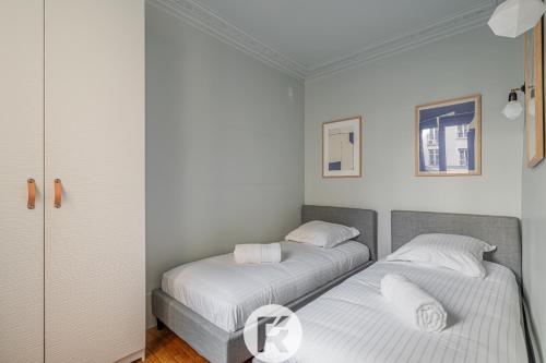 deux lits dans une chambre aux murs blancs dans l'établissement R'Apparts T3 Paris 9ème L'Incontournable, à Paris