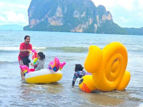 a woman and three children playing on the beach at The Nanda Beach Resort in Sikao