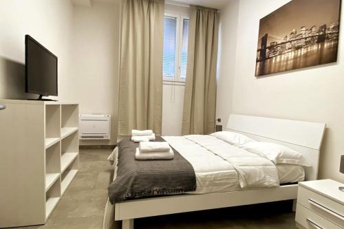 une chambre blanche avec un lit et une télévision dans l'établissement Reno Apartment, à Casalecchio di Reno