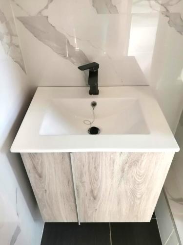 a white bathroom sink with a black faucet at Grey Oak Holiday House in Bulawayo