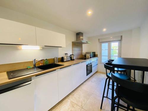 une cuisine avec des armoires blanches et une table et des chaises dans l'établissement Casa : L'éclat du Roi René, à Angers