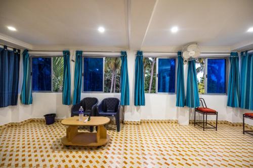 a living room with blue curtains and a table at Sri Sai Holiday Inn in Puducherry