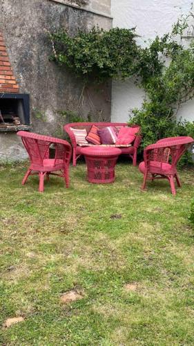 three red chairs and a couch in the grass at Maison de charme Bord de Loire -15mn des plages in Saint-Paimboeuf