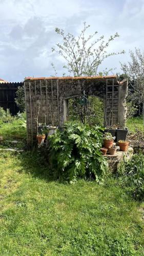 a wooden structure with potted plants in the grass at Maison de charme Bord de Loire -15mn des plages in Saint-Paimboeuf