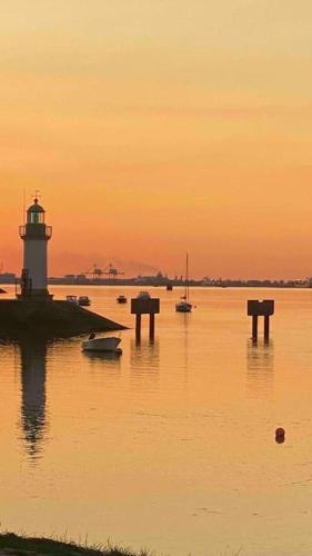 a lighthouse in the water with boats in the water at Maison de charme Bord de Loire -15mn des plages in Saint-Paimboeuf