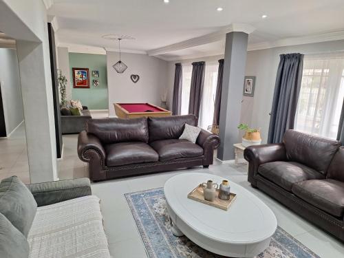 a living room with leather couches and a table at 1 CAMDEBO in Oudtshoorn