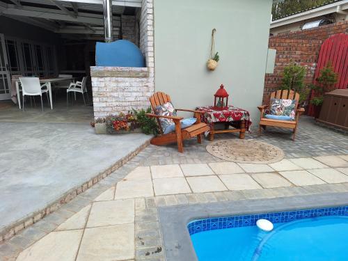 a patio with a table and chairs next to a pool at 1 CAMDEBO in Oudtshoorn