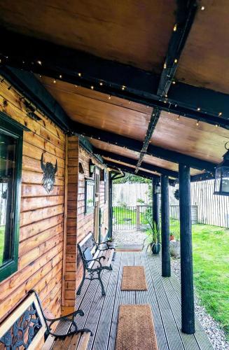 a wooden porch with benches on a house at Cosy wood cabin in rural area near national park in Cumnock