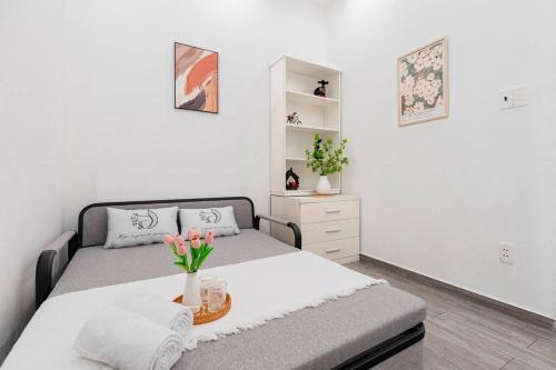 ホーチミン・シティにあるAmieLM Homestay near Airportの花瓶に花が飾られたベッドのある寝室