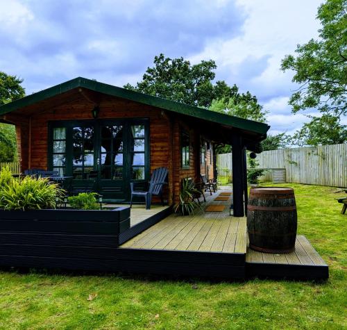 a small cabin with a deck and a barrel at Cosy wood cabin in rural area near national park in Cumnock