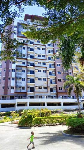 a young child walking in front of a large building at Matina Enclaves 2BR with Wifi Near SM Mall in Davao City