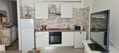 a kitchen with white cabinets and a stove top oven at La Rosa dei Venti a 150 mt dall'Ospedale Pediatrico, a 200 mt dal mare ad a 30 minuti dalla Stazione San Pietro in Santa Marinella