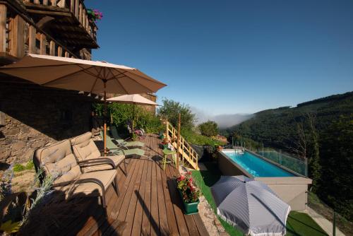 a wooden deck with chairs and an umbrella next to a pool at Talasnal Casas da Urze TER in Lousã
