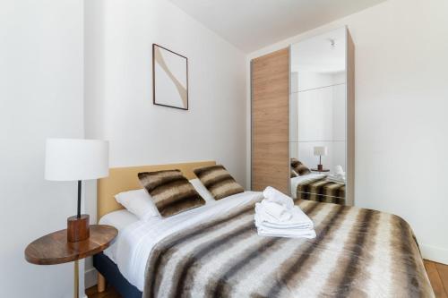 - une chambre avec un grand lit et une couverture rayée dans l'établissement Appartement 33m2 neuf cosy - Paris 12 - 4p - FLAT-GUEST, à Paris
