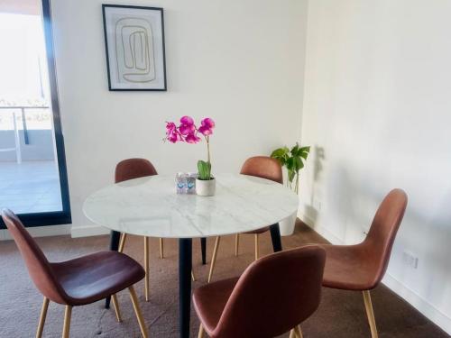a dining room with a white table and brown chairs at Stunning waterfront 3 bedroom condo with Pool, BBQ in Sydney