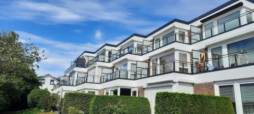 a white apartment building with balconies and bushes at Haus Panorama - Kleines Sternchen in Grömitz