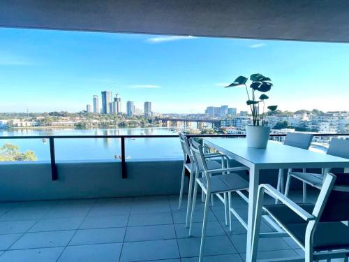 a table and chairs on a balcony with a view of the city at Stunning waterfront 3 bedroom condo with Pool, BBQ in Sydney