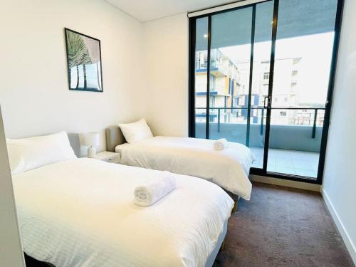 two beds in a room with a large window at Stunning waterfront 3 bedroom condo with Pool, BBQ in Sydney