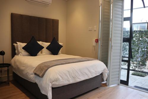 a bedroom with a bed with white sheets and black pillows at The Wantage Suites in Johannesburg