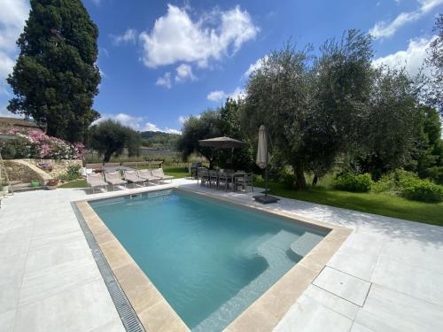 une piscine avec des chaises et un parasol dans l'établissement Bastide de Peyloubet, à Grasse