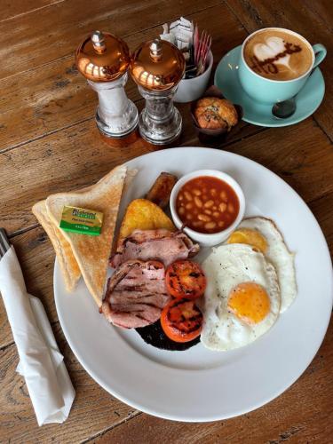 a plate of breakfast food with eggs bacon beans and a cup of coffee at Hayward's at the Grasmere in Keynsham