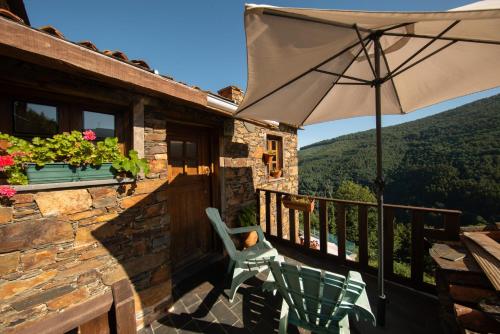a patio with an umbrella and a chair on a balcony at Talasnal Casas da Urze TER in Lousã