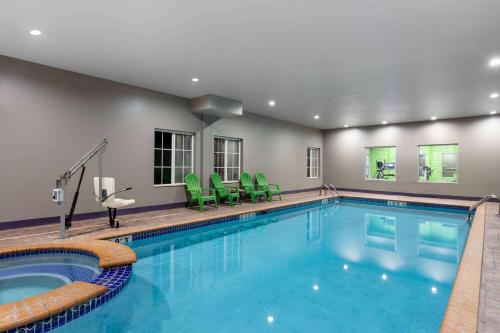 a pool in a hotel with greenchairs and a swimming pool at La Quinta by Wyndham Huntsville Airport Madison in Madison