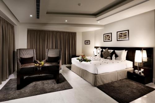 a bedroom with a large bed and two chairs at Aswar Al olaya for serviced Apartments in Al Khobar