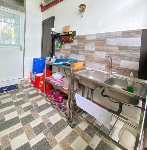 a kitchen with a sink and a tiled floor at Aliyah Transient House in Atimonan