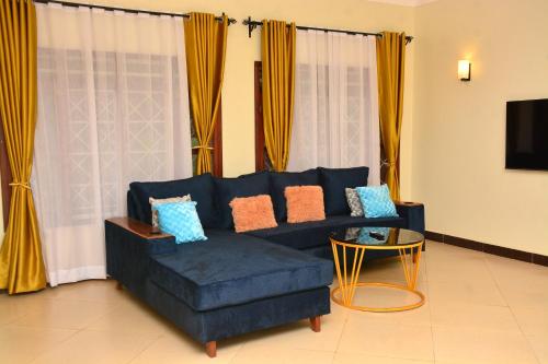 a living room with a blue couch and a table at Kaizen Residences in Entebbe