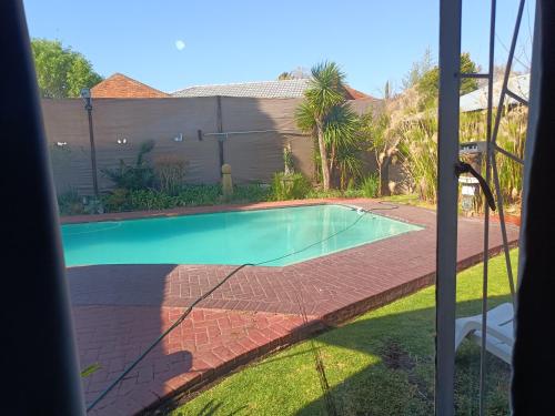 a view of a swimming pool from a window at Ay Jay's Guesthouse in Bloemfontein