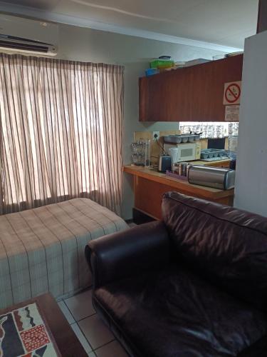 a bedroom with a bed and a couch in a room at Ay Jay's Guesthouse in Bloemfontein