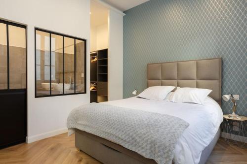 une chambre avec un grand lit et un miroir dans l'établissement Renovated spacious Parisian apt near la Madeleine, à Paris