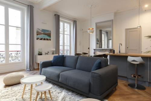 un salon avec un canapé bleu et une table dans l'établissement Renovated spacious Parisian apt near la Madeleine, à Paris