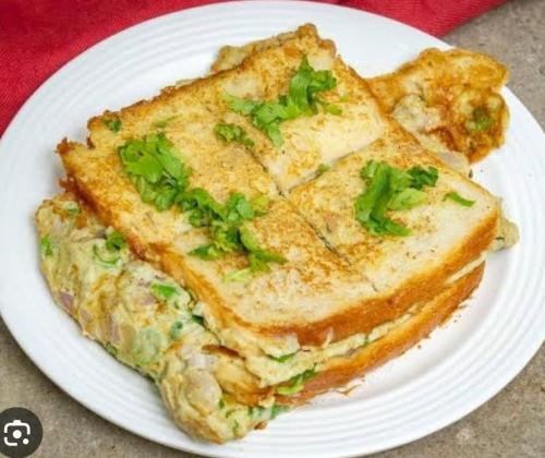 a white plate with a sandwich with cilantro on it at Grand Residency in Bengaluru