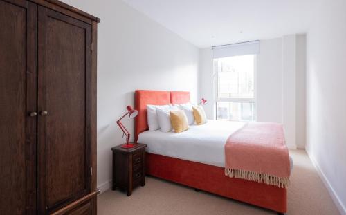 a bedroom with a bed with a red headboard and a window at Native Victoria in London