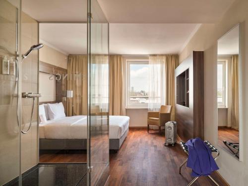 a hotel room with a bed and a glass shower at Flemings Hotel Frankfurt Main-Riverside in Frankfurt/Main