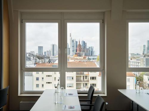 a room with three windows with a view of a city at Flemings Hotel Frankfurt Main-Riverside in Frankfurt/Main