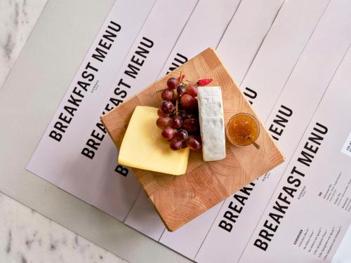 a plate of cheese and grapes on top of a paper at Flemings Hotel Frankfurt Main-Riverside in Frankfurt/Main