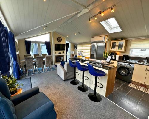 a kitchen and living room with blue stools in a caravan at Sunset 5 - Southview Holiday Park Skegness in Skegness