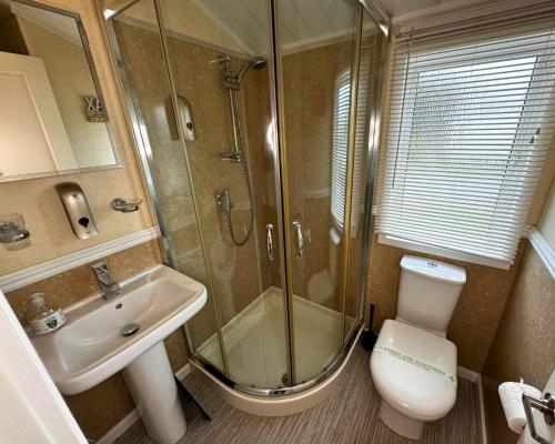 a bathroom with a shower and a toilet and a sink at Sunset 5 - Southview Holiday Park Skegness in Skegness