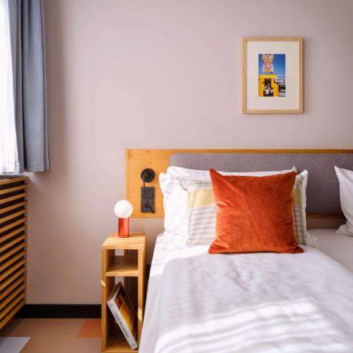 a bedroom with a bed with an orange pillow at Flemings Hotel München-Schwabing in Munich