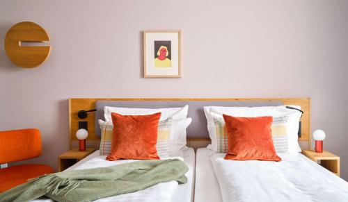 a bedroom with two beds with orange and white pillows at Flemings Hotel München-Schwabing in Munich