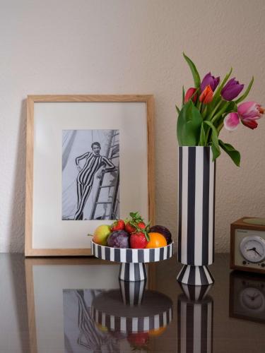a table with a vase of flowers and a plate of fruit at Flemings Hotel München-Schwabing in Munich