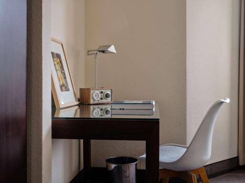 a desk with a chair and a lamp on it at Flemings Hotel München-Schwabing in Munich