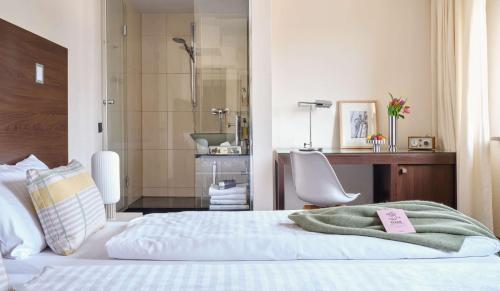 a bedroom with a bed and a bathroom with a shower at Flemings Hotel München-Schwabing in Munich