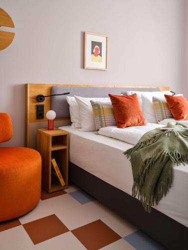 a bed with pillows and a chair in a room at Flemings Hotel München-Schwabing in Munich