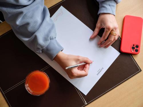 a person signing a piece of paper with a pen at Flemings Hotel München-Schwabing in Munich