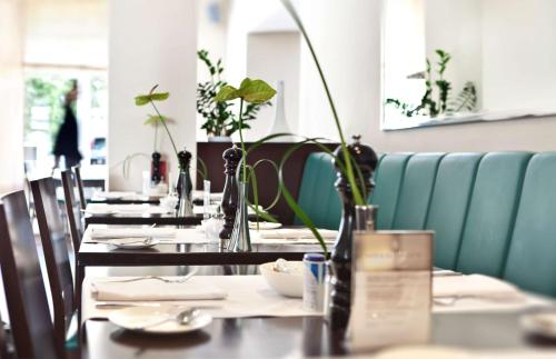 a row of tables in a restaurant with plants at Flemings Hotel München-Schwabing in Munich